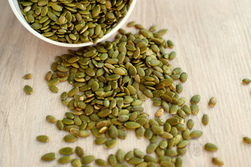 Pumpkin seeds scattered on the table. Many pumpkin seeds spilled out of the package. View from above. Healthy nutrition in the form of pumpkin seeds.