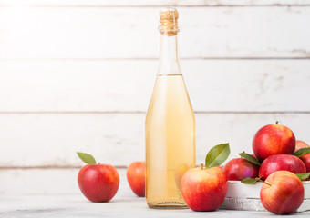 Bottle of homemade organic apple cider with fresh apples in box on wooden background with sun light