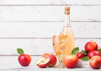 Bottle and glass of homemade organic apple cider with fresh apples in box on wooden background