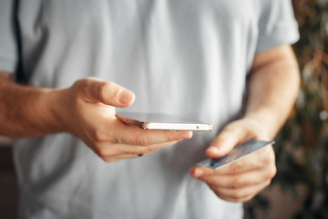 mobile payment and safe online transactions. digital finance and electronic operations. man holding credit card and phone.