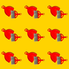Red dustpan and brush lying on yellow background. In the style of pop art. Top view.
