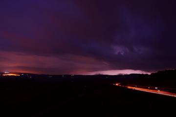 Fototapeta premium Sky with rain clouds at dusk with traces of car lights in the street 
