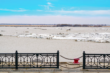 Ice drift, melting of ice on the river during cloudy weather and light snowfall, spring landscape