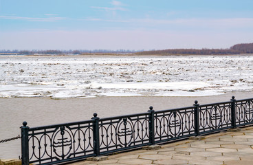 Ice drift, melting of ice on the river during cloudy weather and light snowfall, spring landscape
