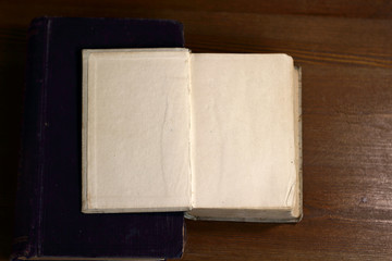 An open old retro book with white blank empty pages on which the designer can write a greeting text or a postcard on the wooden background of the library atmosphere