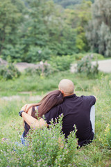 Naklejka na ściany i meble Back view of Romantic Couple in love sitting on grass