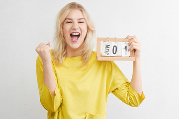 Happy woman in yellow clothes smiles, laughs and rejoices first of June on calendar on white background. Summer vacation, travel, holidays