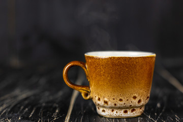 Bright autumn background - cup of coffee on rustic wooden table with place for text. Yellow coffee mug. Bright autumn still life against autumn depression. Coffee break concept. Top view. Copy space