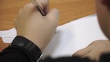 Close-up of the hand of the child writing with the pen in the sheet of paper. Clip. Boy writing with a pen close-up