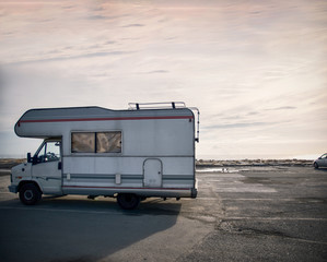 Road trip with a caravan mobile home. Camping caravanning in europe, beach parking. Hippie van, old vintage camper van. Italian coast, mediterranean tourism travel relaxing, leisure, family, driving.
