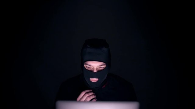 Sexy man in a balaclava takes off his mask and looks into the camera. Man terrorist removes the mask. 