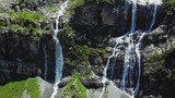 Flight over the Altai mountains. Stunning waterfall aerial view. Waterfall flows into the river