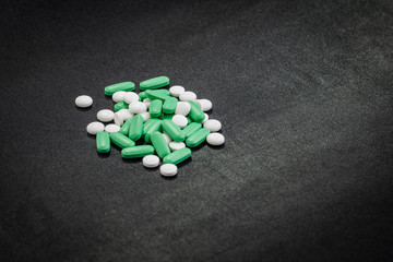 Fototapeta na wymiar different white, green and blue pills on a clean black background.many drugs and abuse of them seriously damages health.