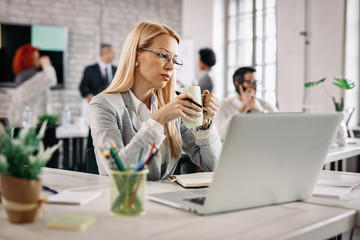 Pensive businesswoman drinking coffee at her desk and thinking of something.
