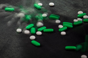 different white, green and blue pills on a clean black background.many drugs and abuse of them seriously damages health.