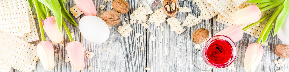 Pesah celebration concept. jewish Passover holiday background with matzo, eggs, spring flowers, wine, green background copy space top view banner