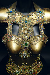 Gorgeous golden corset with precious stones, dark studio background