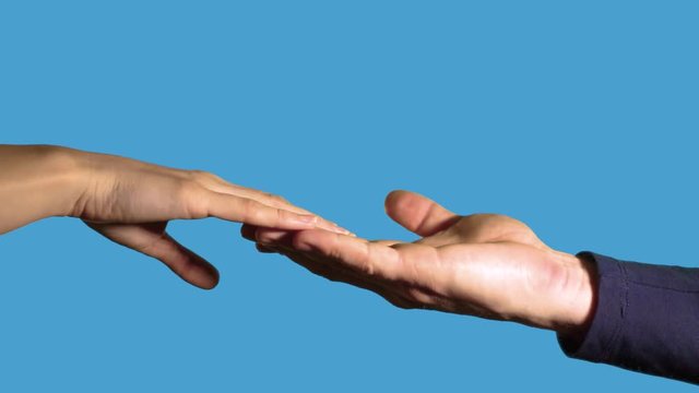 Closeup - Lovely couple holding hands on a blue background, the silhouette of the hand of a man and a woman gently touching each other.