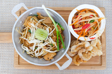 Korat's stir fried noodle served with papaya salad and crispy pork