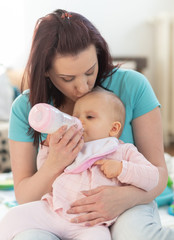 Mother feeding baby girl with bottle