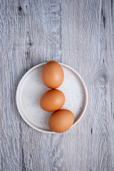 Top view of three eggs on a white plate