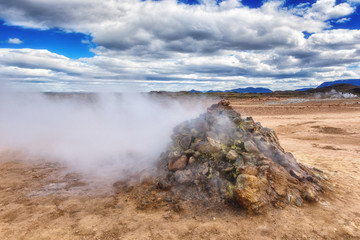 Namafjall Hverir geothermal area in Iceland. Stunning landscape of sulfur valley with smoking fumaroles and blue cloudy sky, travel background, tourist attraction