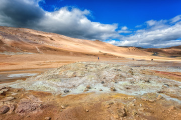 Namafjall Hverir geothermal area in Iceland. Stunning landscape of sulfur valley with smoking fumaroles and blue cloudy sky, travel background, tourist attraction