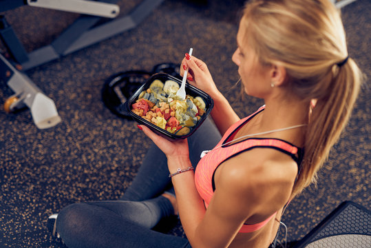 Top View Of Woman Eating Healthy Food While Sitting In A Gym. Healthy Lifestyle Concept.