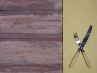 Stainless steel fork and knife with ivory handle on yellow and brown wooden background with copy space