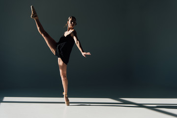 attractive ballerina dancing in black dress and pointe shoes