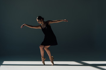 graceful young ballerina dancing in black dress and pointe shoes