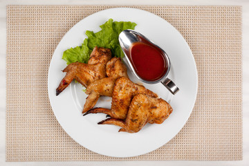 Fried chicken wings on a plate with red sauce.