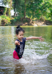 little asian girl playing in the river with water splash