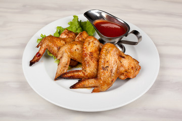 Fried chicken wings on a plate with red sauce.