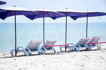 Folding chairs with umbrellas are located on the beach for sleeping and sunbathing.
