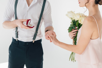 cropped view of man making marriage proposal to girl with bouquet of roses