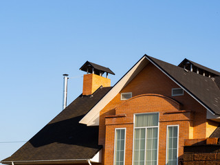 Exterior of new brick house with rectangular windows and chimney on the multilevel roof