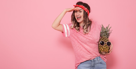 Portrait of a girl with a pineapple on a pink background
