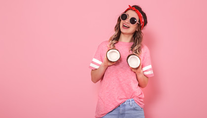 Portrait of a girl with coconuts, on a pink background