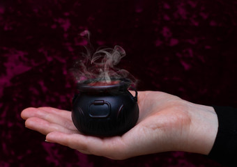 Little magic cauldron with a potion on hand