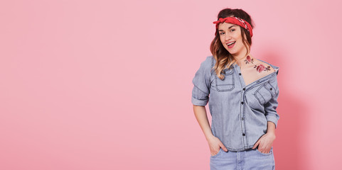 Beautiful young girl in denim shirt with decal water tattoo flowers sticker and smiling on pink...