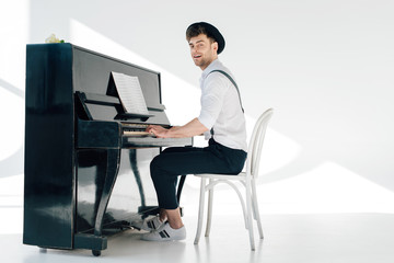 smiling pianist in trendy clothing playing piano