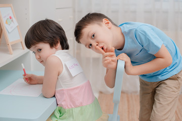Brother sticks a paper fish to the back of the sisters on April fool's Day. Children's humor on April 1. Jokes and fun