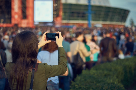 Girl with a phone in her hands in a crowd at an open concert