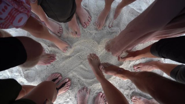Many female and male legs are standing together on sand near the sea, summer holidays concept. Top view feet of people or group of friends on the beach