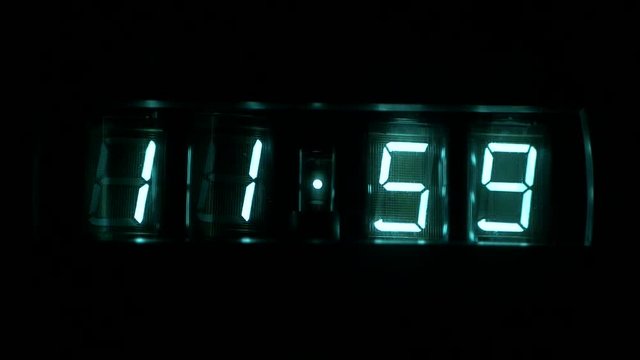 Lamp neon clocks glow in the dark. watch time 11 : 59 to 12 : 00