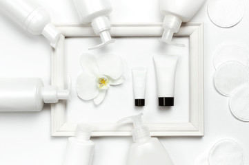 White cosmetic bottle containers, hand or body cream, orchid flower, Photo frame on light background top view flat lay. Cosmetics SPA branding mock-up, Natural organic beauty product concept
