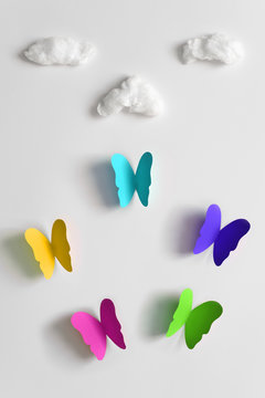 Colorful juicy paper butterflies and fluffy clouds on a white background. Minimal concept.