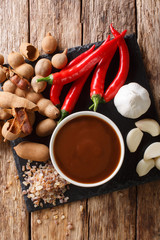 Asian freshly prepared tamarind sauce with ingredients close-up on a table. Vertical top view