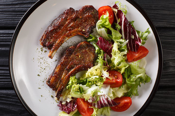 Baked lamb steak with honey served with fresh vegetable salad close-up on a plate. horizontal top view